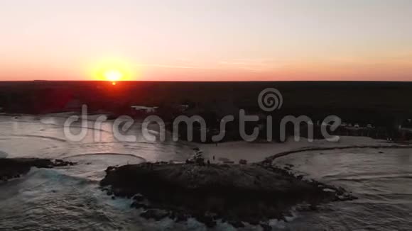 海滩旁的一个岩石码头的空中镜头一群人聚集在一起观看日落视频的预览图