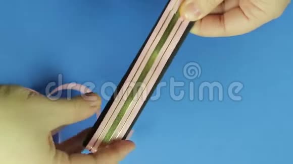 女人手从模板中取出礼品弓的粉红色空白蓝色背景视频的预览图