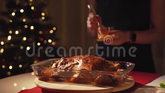 女人手在烤鹅上浇蜂蜜和芥末鹅用苹果和橘子在烤箱里烤圣诞树视频的预览图