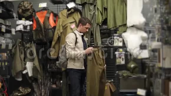 一个成年男子正在一家服装店检查裤子以便徒步旅行和钓鱼视频的预览图