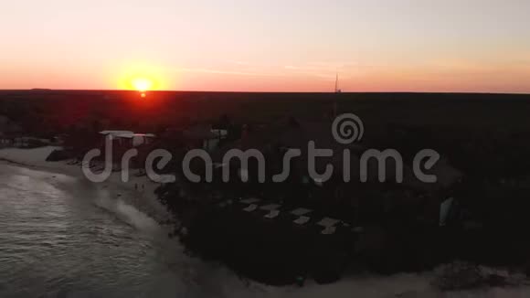 海滩旁的一个岩石码头的空中镜头一群人聚集在一起观看日落视频的预览图