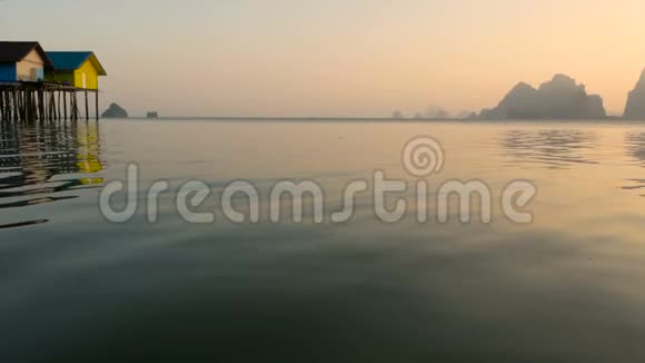 渔夫们房子在日落时从水边上方升起视频的预览图