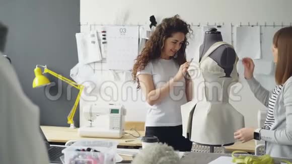 有创意的女服装设计师正在把裁剪出来的布料钉在假人身上同时将女性服装裁剪成视频的预览图