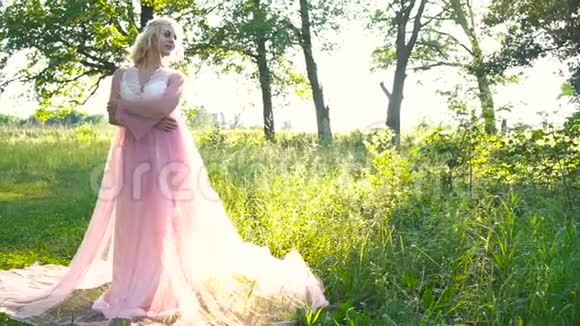 美丽浪漫的女人穿着淡粉色的裙子在清晨的森林里摆姿势美容时尚视频的预览图