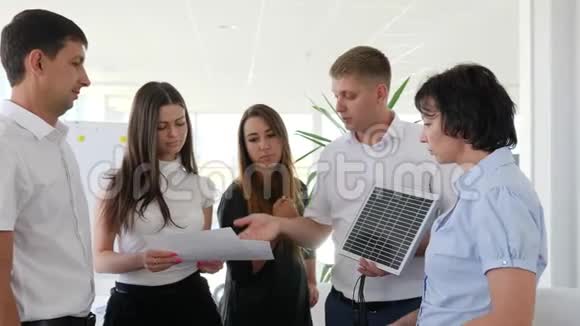 太阳能电池和现代办公室的同事一起交到商人手中视频的预览图
