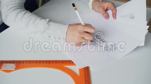 特写倾斜向上拍摄的女性手用铅笔画出女士衣服的草图然后露出迷人的脸视频的预览图