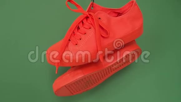 一双红色运动鞋挂在绿色背景上橙色的靴子挂在绳子上视频的预览图