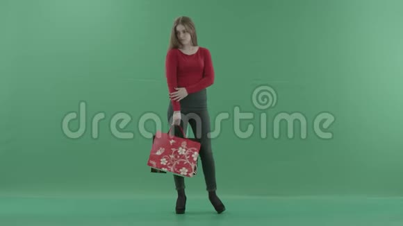 美丽快乐的女人穿着休闲服摆着购物袋她站在一间工作室里反对视频的预览图
