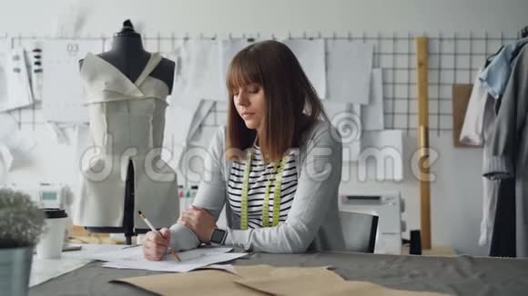 小企业的服装设计师正在为女装画草图并考虑下一个时尚视频的预览图