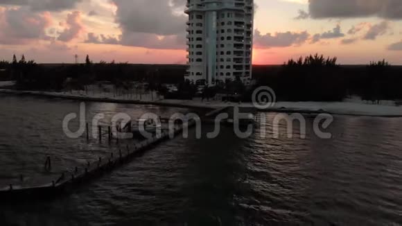 空中拍摄海岸线和一个度假胜地与木船码头日落视频的预览图