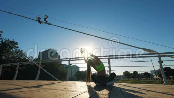 在城市的人行天桥上电影院拍摄活跃的女性剪影锻炼和伸展瑜伽视频的预览图