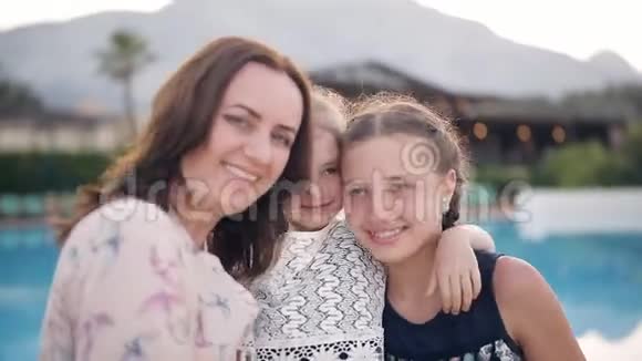 泳池背景下幸福的母亲和两个女儿的画像视频的预览图