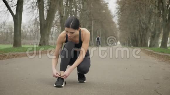 年轻女运动员系好鞋带夏季准备在公园跑步健康的生活方式运动观念视频的预览图