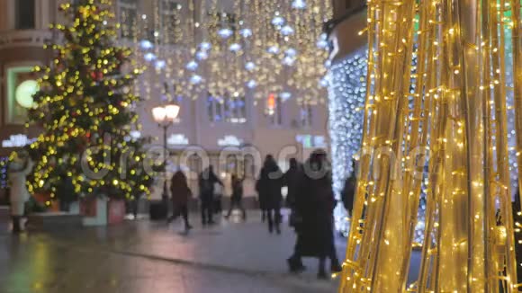 人们走在为节日装饰的街道上的剪影在圣诞灯的背景下离开视频的预览图