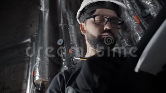有胡子的人戴着白色头盔站在锅炉房里检查视频的预览图