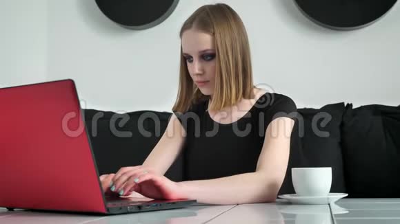 年轻漂亮的女人浓妆艳抹使用笔记本电脑喝咖啡微笑黑白咖啡背景视频的预览图