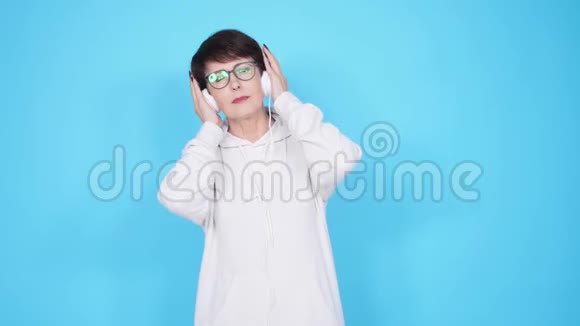 热爱音乐的理念蓝色背景耳机中的成熟女性音乐视频的预览图