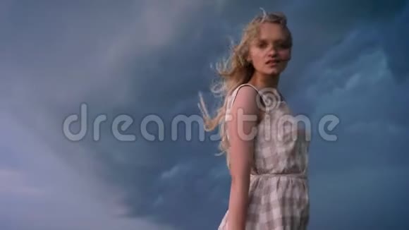 年轻美丽的女孩子在迎风招展在夏日雨天的田野里微笑自由的概念视频的预览图