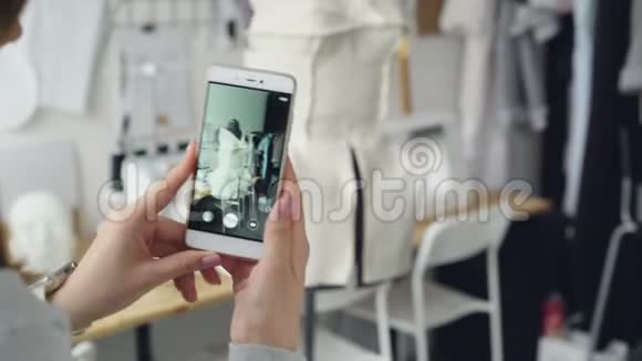 特写镜头女士双手握着智能手机用半件衣服固定在裁剪假人身上视频的预览图