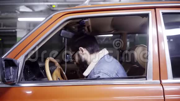 一个留着深色头发的成熟胡子男人关上了地下车库的红色车窗视频的预览图