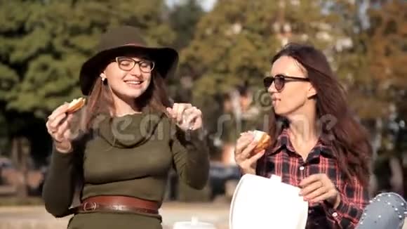 有趣的女孩花时间在公园里笑着吃三明治她们跳舞三明治日假日视频的预览图