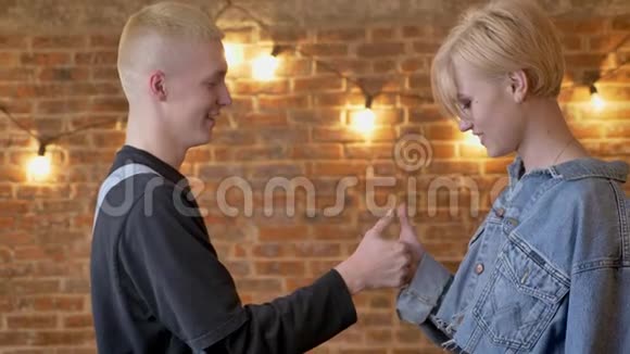 年轻迷人的时髦情侣打拇指大战女朋友获胜沟通观念砖背景视频的预览图