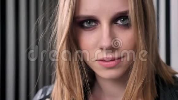 年轻漂亮的女人穿着黑色夹克穿着相机咬着嘴唇穿着条纹墙背景视频的预览图