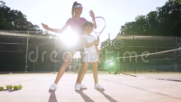 女教练在球场上教小女孩打网球视频的预览图