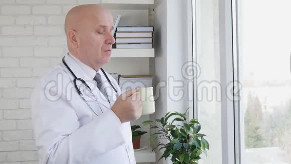 在医院办公室放松的医生喝咖啡或茶的慢动作视频的预览图