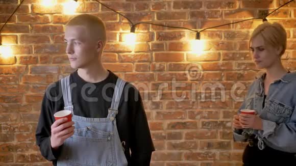 年轻有趣的男孩子正拿着杯子站着他的女朋友正在和他调情接吻法国吻爱视频的预览图