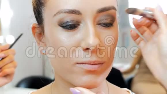 特写4k时装模特脸部镜头专业化妆师在脸上涂睫毛膏和眼影视频的预览图