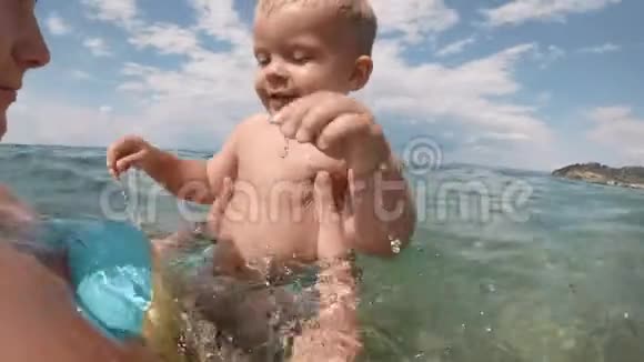 年轻的母亲游泳和玩耍的男孩在海洋或海水阳光明媚的一天户外的自然背景视频的预览图