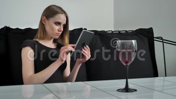 年轻迷人的女人浓妆艳抹看平板坐在沙发上眉头紧锁黑白咖啡色背景视频的预览图
