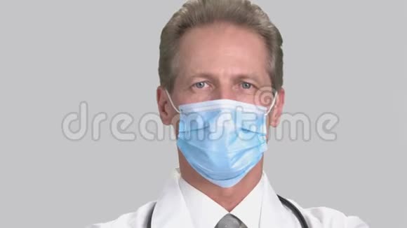 戴白色手术面罩的严肃男子医生的特写肖像视频的预览图