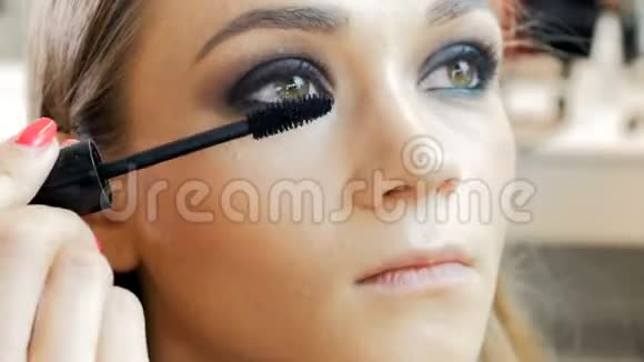 特写4k时装模特脸部镜头专业化妆师在脸上涂睫毛膏和眼影视频的预览图