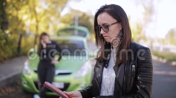 一辆绿色汽车上的两名妇女敲打车轮在道路上安装紧急标志视频的预览图