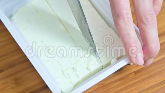女性手的特写用一包白色的feta奶酪切一把刀做成希腊色拉的立方体视频的预览图