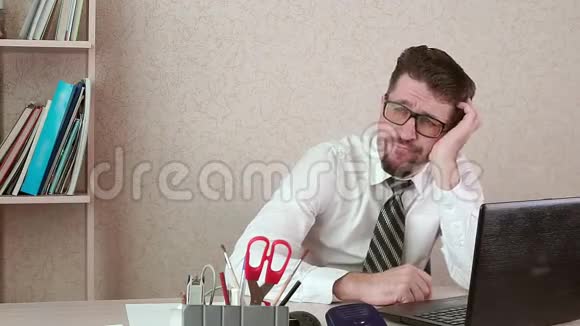 一个留着胡子和眼镜的男性办公室工作人员错过了他的笔记本电脑视频的预览图