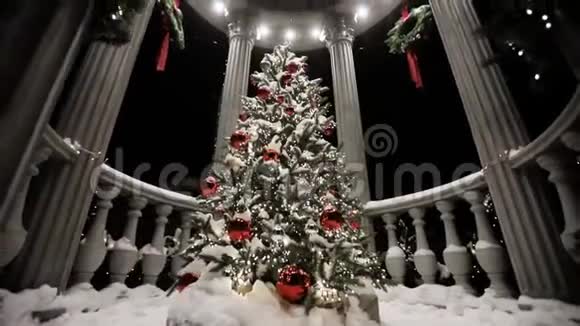 神奇的圣诞树在降雪之夜的街道上的凉亭中覆盖着雪视频的预览图