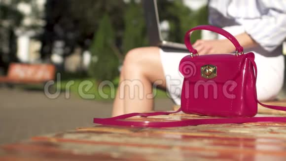 女人合上她的笔记本电脑从公园的长凳上拿出她的粉红色包走了视频的预览图