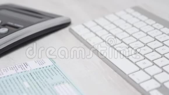 电脑键盘旁桌子上妇女填税表1040及计算退税的及计算退税视频的预览图