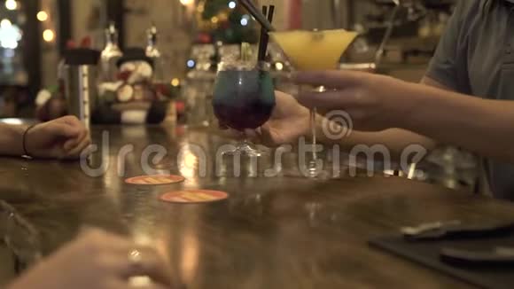 酒保把酒精鸡尾酒放在酒吧桌上供客户在晚上的咖啡馆人们常喝鸡尾酒杯视频的预览图