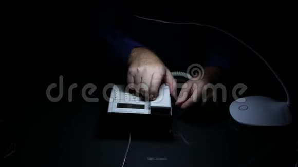 商务人员双手放在黑暗的房间深夜使用固定电话视频的预览图