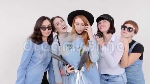 一群穿牛仔服装的女人在白色的工作室里摆姿势手里拿着一束花戴眼镜和帽子的妇女视频的预览图