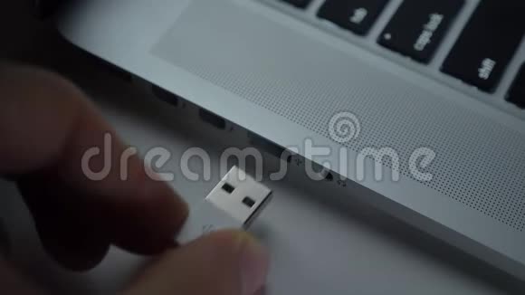 特写镜头的手快速插入白色USB电缆到笔记本电脑的黑桌背景视频的预览图