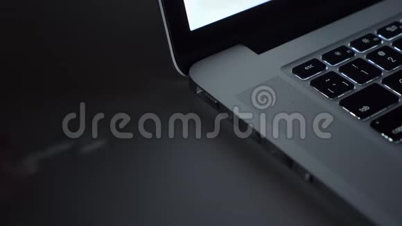 特写镜头的男性手快速插入电线到笔记本电脑它点亮彩色的黑色桌子背景视频的预览图