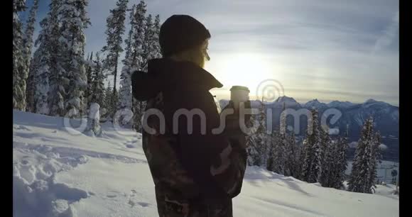 喝咖啡的女人站在白雪覆盖的风景上视频的预览图