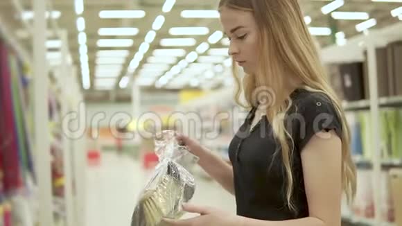 年轻女子正在超市里买一包带刷子的铲子视频的预览图