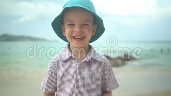 肖像可爱的男孩戴着帽子在海滩上笑视频的预览图