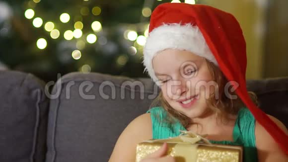 快乐的孩子打开圣诞礼盒卧室里戴着圣诞老人帽子的滑稽宝宝孩子微笑的肖像视频的预览图